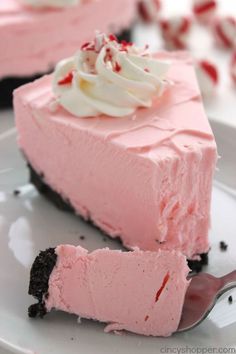 a slice of pink cheesecake with whipped cream on top and chocolate shavings around the edges