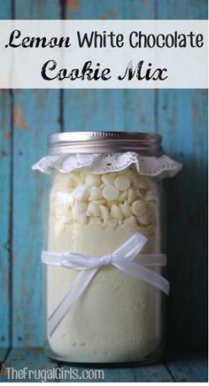 a jar filled with cake mix sitting on top of a blue wooden table next to a white ribbon