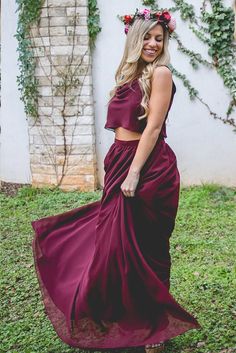 a woman wearing a maroon dress and flower crown standing in the grass with her hand on her hip