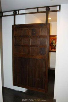 an old wooden door with metal bars on the top and bottom, in front of a white wall