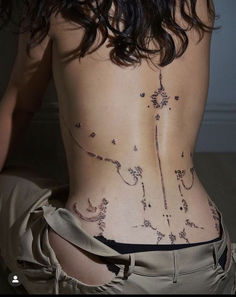 the back of a woman's body with tattoos on her lower and lower back