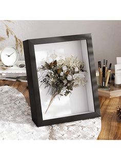 a vase with flowers in it sitting on a table next to a clock and other items