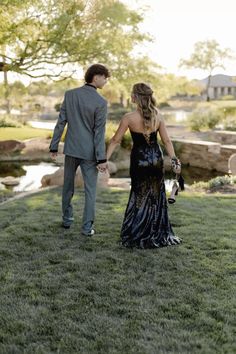 a man and woman holding hands walking in the grass