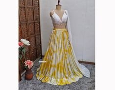 Made to Order/Measurement/Custom Order Lehenga - Color : Yellow and Off White Ties and Dye Print - Fabric : Georgette with Silver Stripes - Flared Gathered Lehenga Skirt  - Offwhite Blended Raw Silk Spaghetti Blouse with Embroidered Cape Dupatta - Drawstring closure with designer latkan - Soft can can attached PLEASE NOTE: BUYERS ARE RESPONSIBLE FOR ANY CUSTOMS AND IMPORT TAXES THAT MAY APPLY. Fabric Care : Dry Clean Only Disclaimer: Please note the photographs are taken by mobile camera in sunlight The actual color of the product might slightly differ due to exposure of light or monitor's display Shipping: This is made to order product. We customize the pattern of the dress to suit your style and fitting. Once you place the order we will provide you with a template for measurements (to be Yellow Tie And Dye Lehenga, Elegant Yellow Skirt For Wedding, Yellow Lehenga Color Combos, White Lehenga For Summer Reception, Summer Wedding Set With Pallu, Summer Wedding Sets With Pallu, White Summer Choli For Wedding, Yellow Summer Wedding Lehenga, Summer Wedding Yellow Lehenga