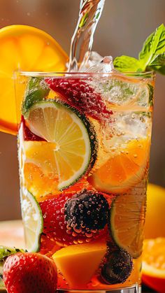 a glass filled with fruit and water on top of a table