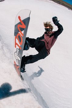 a man riding a snowboard down the side of a snow covered slope