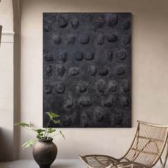 a chair and vase on a table in front of a wall covered with black circles