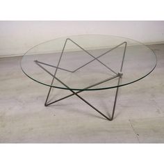 a glass and metal coffee table with star design on the top, sitting on concrete flooring