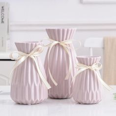 three pink vases with bows on them sitting on a table next to each other