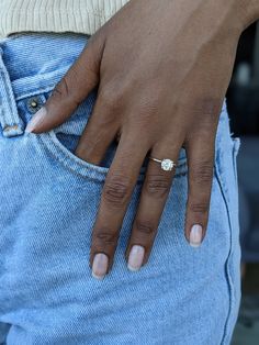 a close up of a person's hand with a diamond ring on their finger