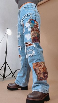 a person standing in front of a camera wearing jeans with patches on them and brown shoes