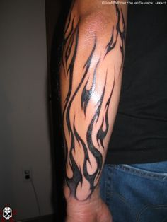 a man's arm with black and white flames tattoo on his left arm,