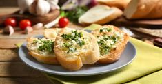 two pieces of bread on a plate with cheese and herbs in the middle next to garlic bread