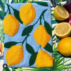 a towel with lemons and leaves on it next to some fruit that is cut in half