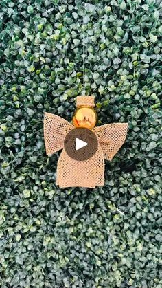 an overhead view of a toy angel hanging from a string on top of a green bush