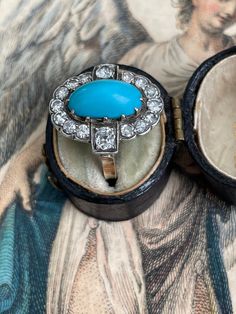 A bright robin's egg blue turquoise cabochon is perfectly framed in halo of sparkling single-cut and old mine-cut diamonds. This Edwardian treasure is crafted in platinum topped 14k yellow gold. Currently a finger size 4.5. Measurements: 18.80 x 17.12 mm Turquoise: 12.61 x 6.77 x 6.45 mm deep, lovely matrix on the back Diamonds: 14 single-cut diamonds estimated .50 total carats, two old mine-cut diamonds estimated .30 total carat weight. I-J range in color, SI2 - I1 range in clarity Metal: plati Turquoise And Diamond Ring, Quartz Properties, Robin's Egg Blue, Robins Egg Blue, Star Pictures, Diamond Cluster Ring, Diamond Cluster, Blue Turquoise, Black Enamel