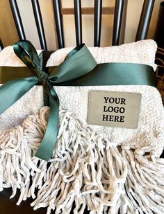 a white blanket with a green ribbon tied around it on top of a wooden chair