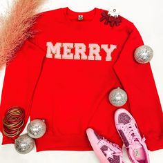 A long sleeve crew neck sweatshirt that is bright green with Merry across the chest in pink chenille letters with gold trim. Pictured on a white background with sneakers, gold and pink jewelry, and Christmas ornaments. Festive Long Sleeve Fall Sweatshirt, Winter Loungewear Tops With Letter Embroidery, Christmas Long Sleeve Sweatshirt With Embroidered Text, Red Letter Embroidery Sweatshirt For Fall, Winter Letter Embroidery Sweatshirt For Loungewear, Red Embroidered Text Sweatshirt For Fall, Winter Loungewear Sweatshirt With Letter Embroidery, Red Sweatshirt With Letter Embroidery For Winter, Red Letter Embroidery Sweatshirt For Winter