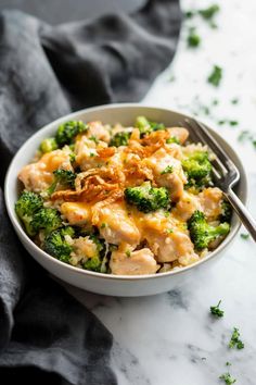 a bowl filled with chicken and broccoli on top of a white tablecloth