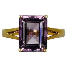 Make an instant statement with this pre-loved 9k yellow gold ring featuring a striking natural emerald-cut amethyst. This ring effortlessly combines boldness with minimalist sophistication, ideal for anyone who loves a standout piece without compromising on elegance. The deep purple hue of the amethyst is perfectly accentuated by the sleek emerald cut, creating a timeless design. Originating from England and stamped for authenticity, this ring is ready to be worn and adored once more. Materials: Square Cut Amethyst Ring For Formal Occasions, Classic Emerald Cut Amethyst Ring, Classic Emerald-cut Amethyst Ring, Formal Square Cut Amethyst Ring, Classic Amethyst Ring With Rectangular Stone For Formal Occasions, Rectangular Amethyst Ring In Yellow Gold, Formal Purple Amethyst Ring With Rectangular Shape, Formal Rectangular Purple Amethyst Ring, Formal Rectangular Amethyst Ring