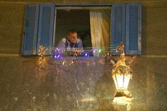 a man is looking out the window at christmas lights