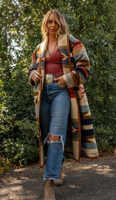 Wyeth Trail Long Stadium Coat Our Wyeth Trail Long Stadium Coat will keep you covered from top to below the knee. Made from the Pendleton Wyeth Trail wool blanket, the warm earth tone colors are easy to wear. Wear it open or close at the waist with a toggle. Designed for a slightly oversized fit and look. The Wyeth Trail blanket reflects warm, harmonious colors of ancient corn varieties patterned in rows similar to ancient Native American gardens. Arrows point in two directions, the past and the Pendleton Sweater Outfit, Nfr 2024 Outfits, Western Thanksgiving Outfit, Warm Clothes Outfits, Jackson Hole Outfits, Blanket Coat Pattern, Yellowstone Outfit Ideas, Native American Poncho, Southwest Style Clothing