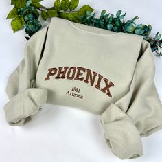 Phoenix Embroidered Sweatshirt Message me for other cities! -Embroidered Sweatshirt   - Unisex Sweatshirt -Gildan brand *(jerseesor Port & Co brands may be used to fulfill any back orders that may occur) - Design is 6.8in wide for all  sweatshirt sizes  please message me for any questions. Thank you! Fall College Embroidered T-shirt, Embroidered Fall College T-shirt, Embroidered Graphics T-shirt For College In Fall, Casual Tops With Custom Embroidery For College, Fall College T-shirt With Embroidered Logo, College T-shirt With Embroidered Logo For Fall, Embroidered Text T-shirt For College In Fall, Embroidered Relaxed Fit College T-shirt, Cotton Sweatshirt With Letter Embroidery For Campus