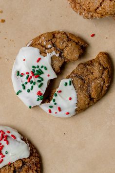 two cookies with white frosting and sprinkles are on a piece of paper