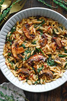 pasta with shrimp and spinach in a white bowl on top of a wooden table