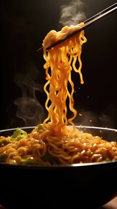 noodles being lifted from a pan with chopsticks over them and steam rising up