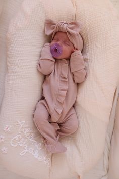 a baby is sleeping with a pacifier in it's mouth and wearing a pink outfit