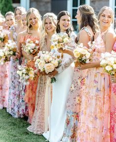 a group of women standing next to each other holding bouquets in their hands and smiling