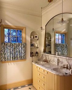 a bathroom with two sinks and a large mirror in the middle of it, next to a window