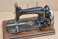 an old fashioned sewing machine sitting on top of a wooden stand