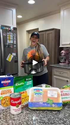 a woman standing in a kitchen holding an instant pot with ingredients on the counter top