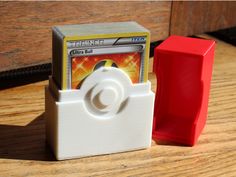 a small plastic object sitting on top of a wooden table next to a red container