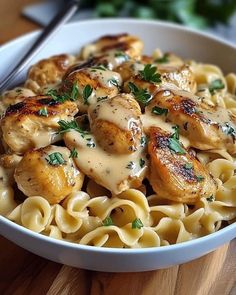 a white bowl filled with pasta and chicken covered in sauce