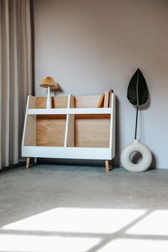 a white book shelf with books and toys on it next to a window in a room