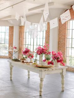 a table with pink flowers on it in front of windows