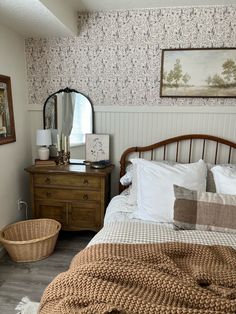 a bed sitting next to a wooden dresser under a mirror on top of a wall