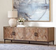 a living room with a large painting on the wall and a sideboard in front of it