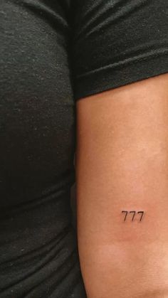 a woman's arm with a small tattoo that reads 777 on the side