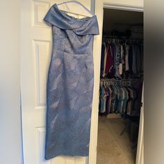 a blue dress hanging on the wall next to a closet