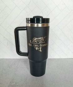 a stainless steel travel mug with the words reel cool grandpa on it and a black lid