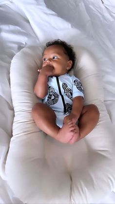 a baby laying on top of a white pillow