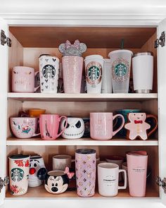 the shelves are filled with starbucks mugs and other coffee cups in pink, white, and black