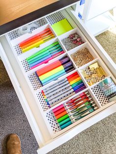 a drawer filled with lots of different colored pens and pencils on top of it