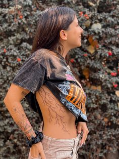 a woman with tattoos standing in front of a bush