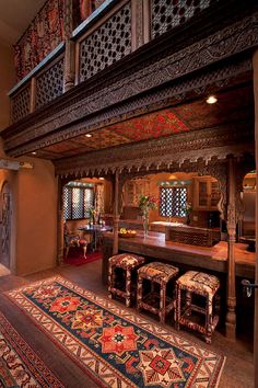 an ornately decorated living room with two stools and a rug on the floor