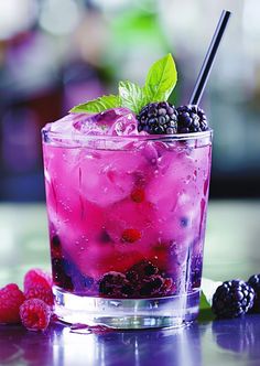 a glass filled with ice and berries on top of a table